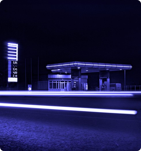 Stazione di servizio illuminata di notte con scie luminose in movimento e insegna prezzi visibile