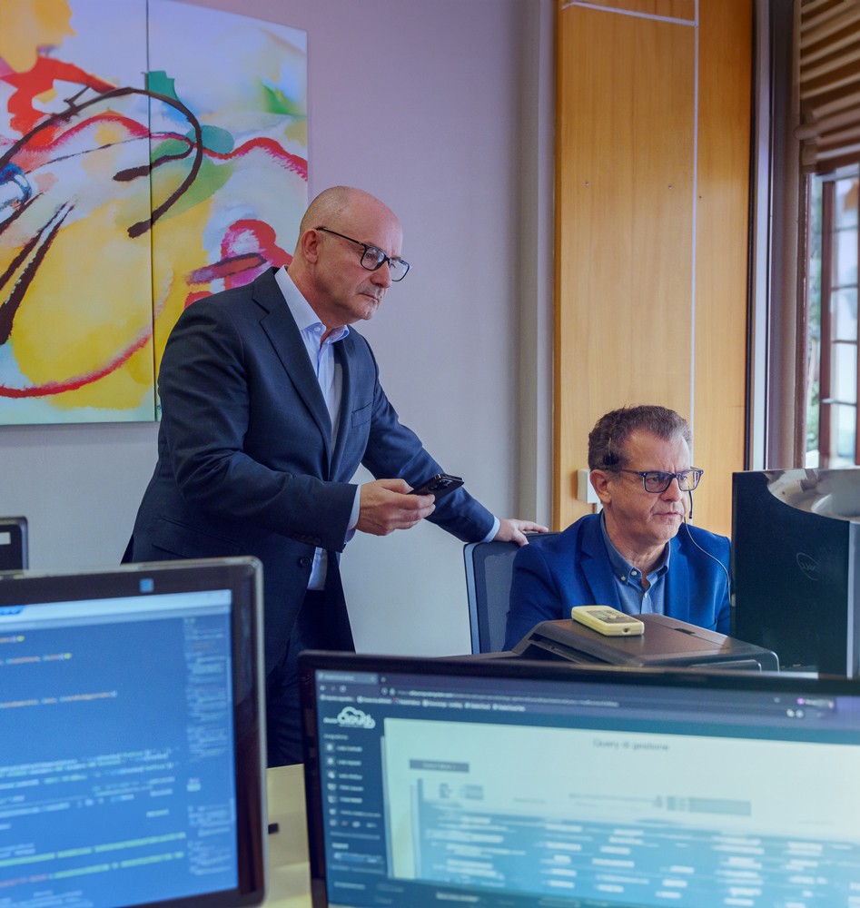 Team tecnico al lavoro con codice su schermo, soci di Alfa Computer System a confronto operativo in ufficio