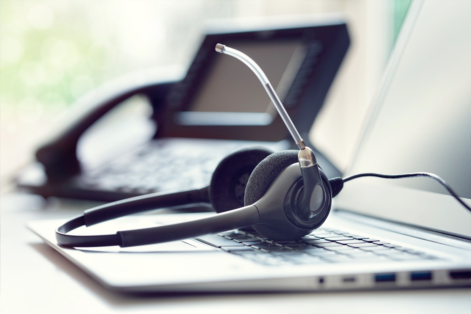 Cuffie con microfono appoggiate su un laptop, simbolo di assistenza tecnica e supporto clienti