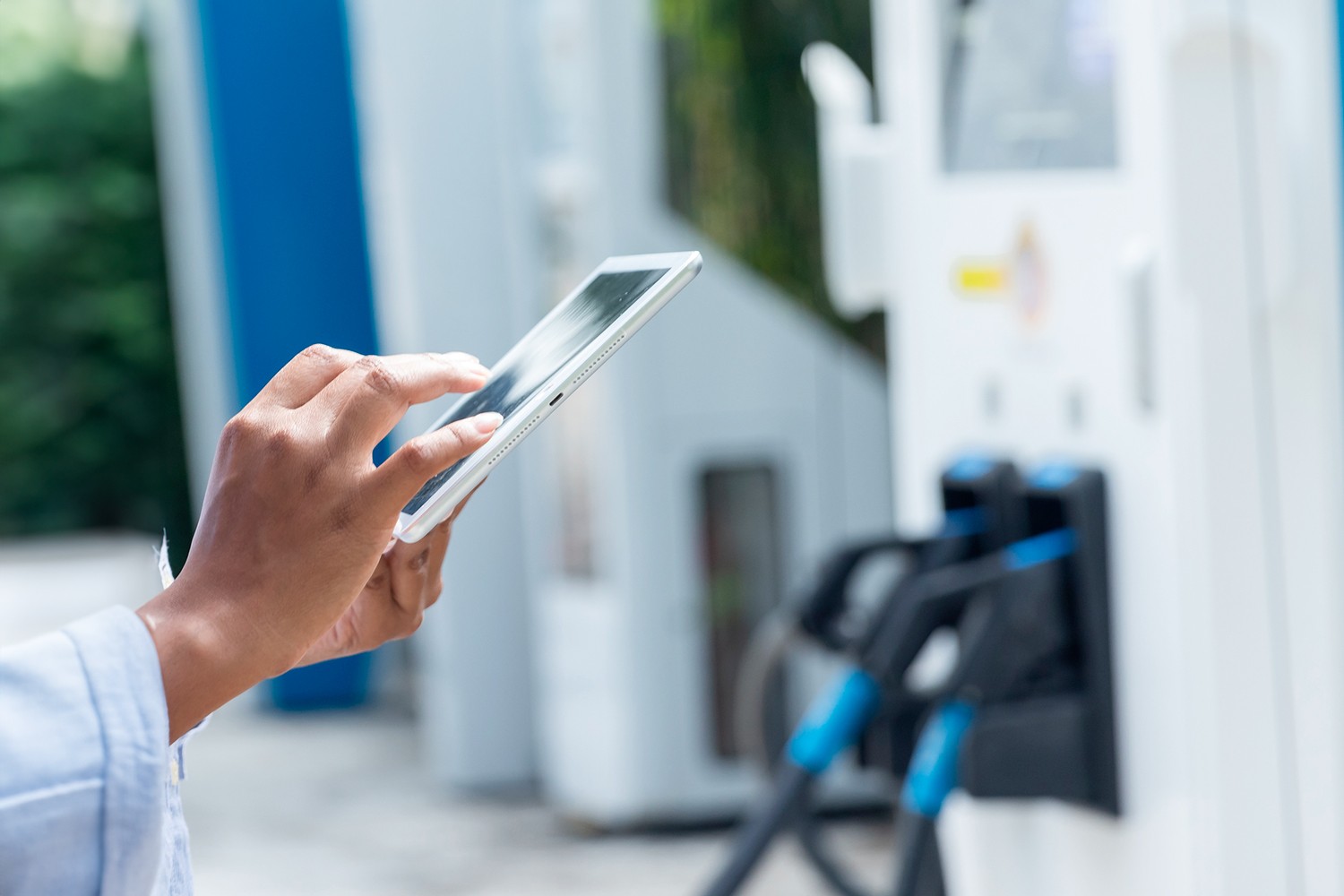 Persona utilizza un tablet davanti a una pompa di carburante, simbolo di digitalizzazione nel settore fuel